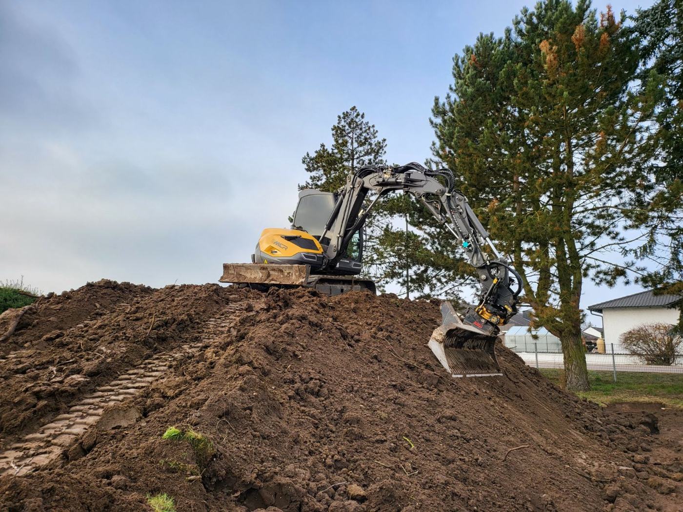 Erdarbeiten – Bagger beim Modellieren eines Erdwalls
