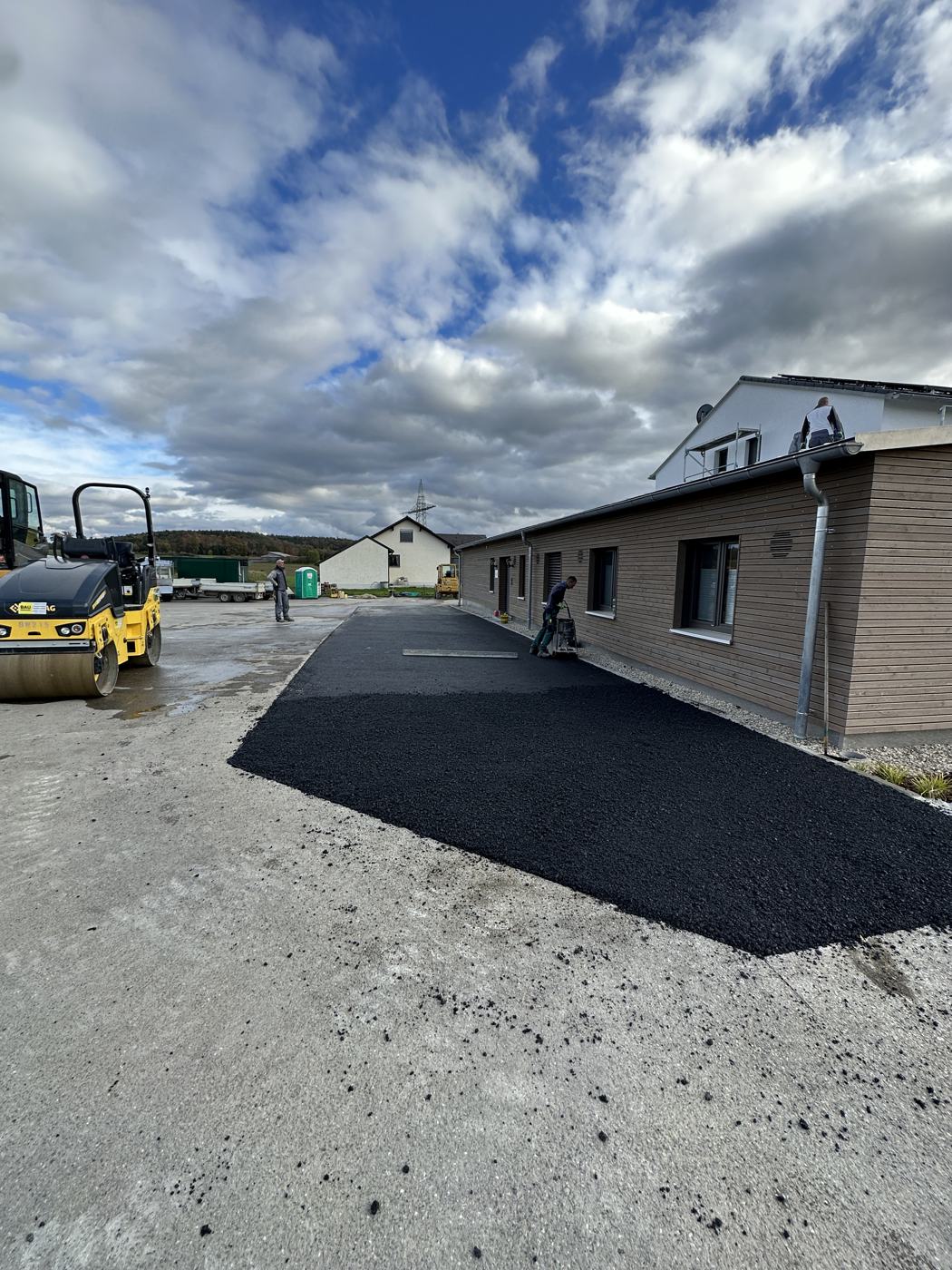 Frisch asphaltierte Fläche mit Walze im Hintergrund